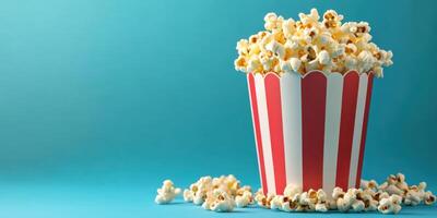 Freshly popped popcorn in a classic striped container on a vibrant blue background photo