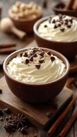 Creamy whipped topping with chocolate shavings and spices served in rustic bowls on a wooden table photo