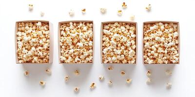 Popcorn served in four boxes arranged on a white surface, with scattered pieces around them photo
