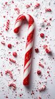 Festive holiday candy cane surrounded by scattered peppermint treats and snow-like sprinkles on a bright background photo