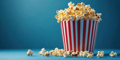 Deliciously fresh popcorn in a striped bucket on a vibrant blue background at a cinema or movie night setting photo