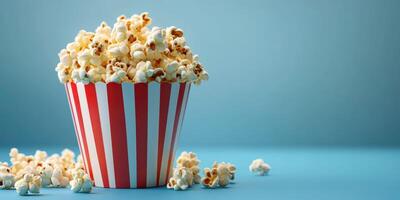 Delicious popcorn served in a striped container on a blue background perfect for movie night or snack time photo