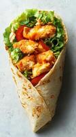 Delicious crispy chicken wrap with fresh vegetables and creamy sauce served in a soft tortilla photo