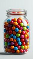 Colorful candy jar filled with vibrant round sweets in various hues displayed against a neutral background photo