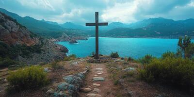 Cross overlooking a stunning coastal landscape with turquoise waters and dramatic mountains in the background photo