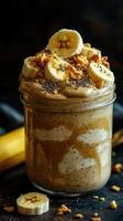 Delicious banana smoothie topped with granola and chia seeds served in a glass jar photo