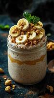 Delicious layered banana parfait with granola and mint on a dark textured background photo