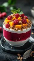 Refreshing yogurt parfait topped with mango, raspberries, and granola served in a stylish bowl photo