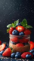 Fresh berries layered in a glass jar with mint leaves and a dark background create a vibrant dessert display photo