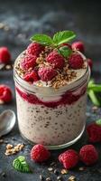 Delicious raspberry parfait with granola and chia seeds topped with fresh mint leaves photo