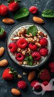 Bowl of yogurt topped with fresh strawberries and raspberries, surrounded by almonds and mint leaves photo