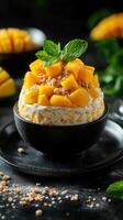 Delicious mango dessert topped with fresh fruit and crunchy nuts in a stylish black bowl photo