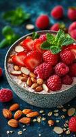 Healthy bowl of yogurt topped with strawberries and raspberries on a blue background photo