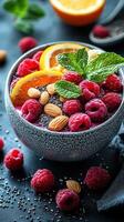 Colorful chia seed bowl topped with fresh raspberries, orange slices, and almonds on a dark background photo