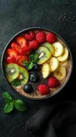 Colorful fruit bowl with sliced strawberries, bananas, and kiwis arranged on a dark background photo