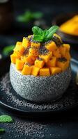 Chia pudding topped with fresh mango and mint leaves served on a dark table photo