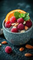 Chia seed pudding topped with fresh raspberries, orange slice, and almonds served in a speckled bowl photo