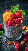 Chia pudding topped with fresh raspberries, oranges, and almonds captured on a black stone surface photo