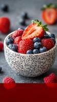 Fresh mixed berries in a ceramic bowl with vibrant colors and textures on a dark background photo