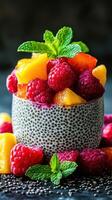 Fresh fruit salad with vibrant raspberries, peaches, and mint in a textured bowl on a dark surface highlighted by natural light photo