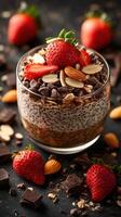 Delicious dessert featuring chia seeds, chocolate, strawberries, and almonds arranged elegantly in a glass cup photo