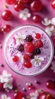 Colorful berry smoothie topped with fresh fruits and flowers on a vibrant pink background photo