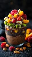 Colorful fruit parfait with chia seeds and nuts in a glass on a dark background photo