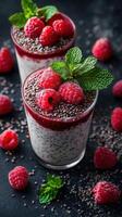 Delicious raspberry chia seed pudding served in clear glasses on a dark surface with fresh raspberries and mint photo