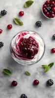 Delicious dessert topped with berry compote surrounded by fresh fruits and mint leaves photo
