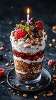Delightful dessert featuring layers of yogurt, granola, and fresh berries topped with a birthday candle at a celebration photo