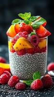 Chia seed pudding topped with fresh strawberries, mango, and raspberries in a glass cup on a dark background photo