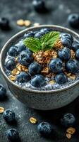 Healthy breakfast bowl with fresh blueberries and crunchy granola garnished with mint leaves at a cozy kitchen setting photo