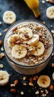 Creamy banana parfait with granola and chia seeds in a glass bowl on a dark surface photo