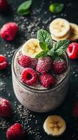 Delicious chia seed pudding topped with fresh raspberries and banana slices on a dark backdrop photo