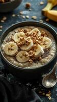 Healthy breakfast bowl with banana slices, granola, and chia seeds topped with oatmeal in a dark setting photo