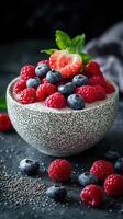 Fresh berries with chia seeds in a textured bowl on a dark surface with mint garnish and scattered fruit photo