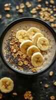 Healthy breakfast bowl with banana slices, chia seeds, and oats served in a black bowl on a dark surface photo