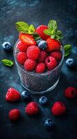 Fresh berries and mint leaves arranged in a glass on a dark background create an appealing dessert display photo