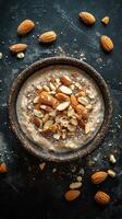 Delicious almond topped oatmeal bowl served on a dark stone surface with scattered almonds around it photo
