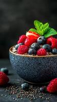 Berry bowl with chia seeds and mint garnishment on a dark background photo