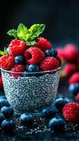 Chia seed pudding topped with fresh raspberries and blueberries in a glass bowl on a dark backdrop photo