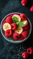 Delicious smoothie bowl topped with banana slices and fresh raspberries on a dark background in a cozy kitchen setting photo