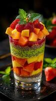 Colorful fruit parfait served in a clear glass garnished with mint leaves during a summer gathering photo