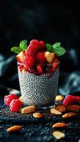 Chia pudding topped with fresh raspberries and strawberries in a glass bowl surrounded by almonds photo