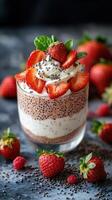 Delicious layered dessert with strawberries and chia seeds served in a glass on a dark kitchen countertop photo