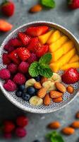 Chia seed pudding topped with fresh fruits including strawberries, mango, raspberries, bananas, and almonds on a gray background photo