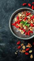 Healthy chia seed pudding topped with nuts and goji berries in a stylish bowl on a dark surface photo