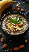 Healthy banana oatmeal bowl topped with almonds and chia seeds served on a dark background photo
