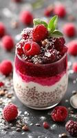 Delicious raspberry parfait served in a glass with layers of yogurt, chia seeds, and topped with fresh berries photo