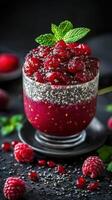 Colorful raspberry chia dessert served in a glass with fresh mint on a dark background photo